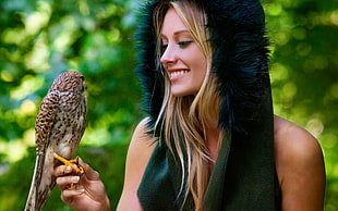 woman in black fur hat with brown bird on hear right hand